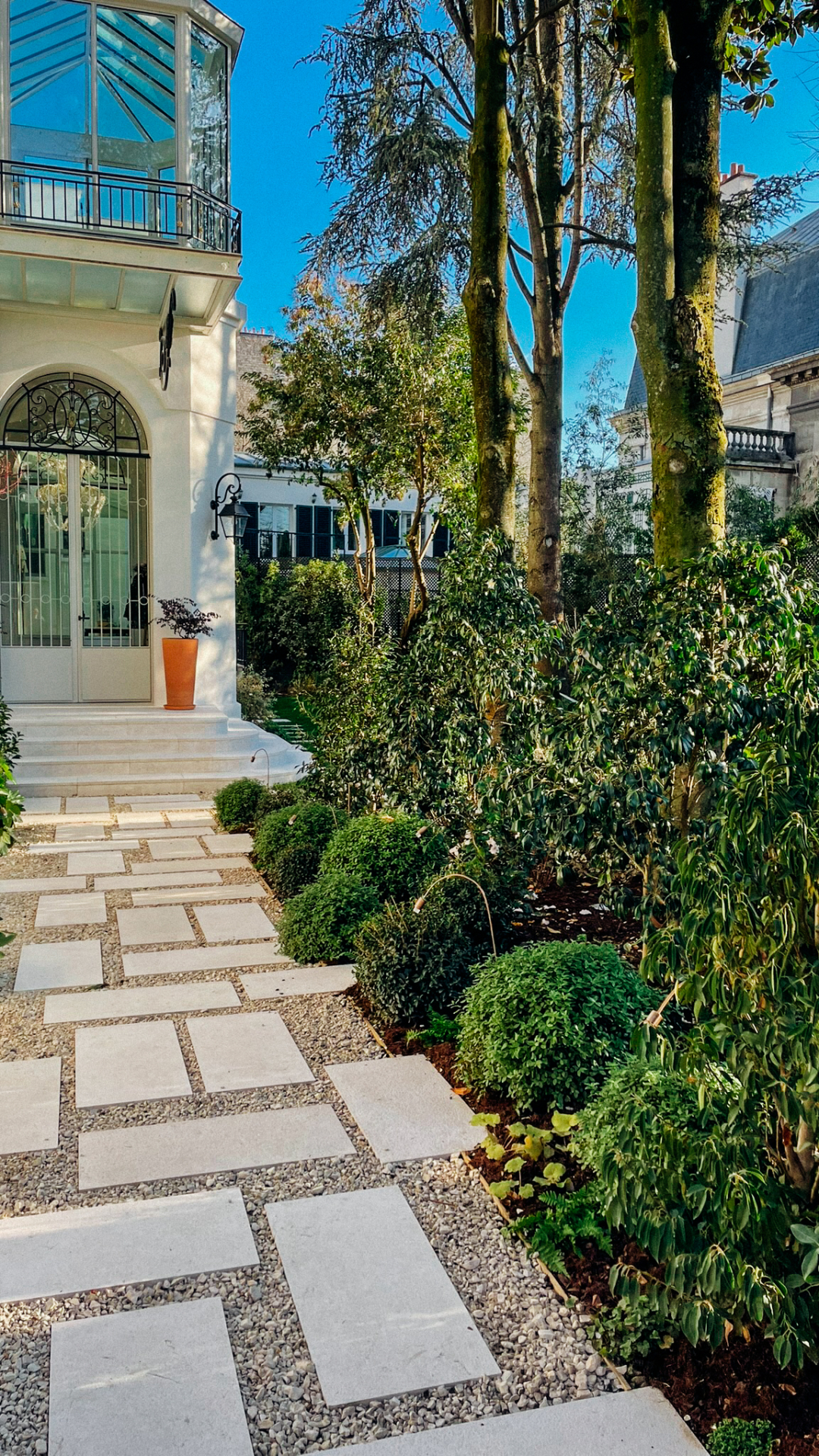 Aménagement d'un jardin à Paris réalisé en 2023 par notre bureau d'études paysagiste, avec allée en pas japonais, massifs paysagers et végétation élégante autour d'une demeure de caractère.