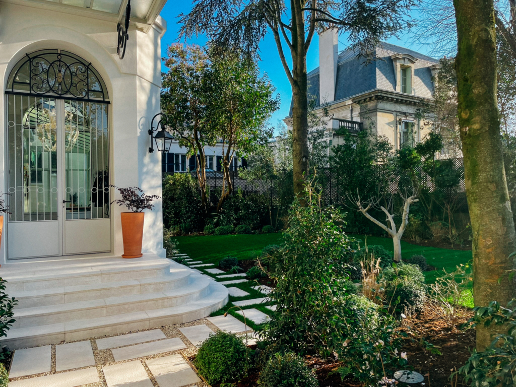 Aménagement d'un jardin à Paris réalisé en 2023 par notre bureau paysagiste, avec allées en pas japonais, pelouse, massifs paysagers et végétation soignée autour d'une demeure de caractère.