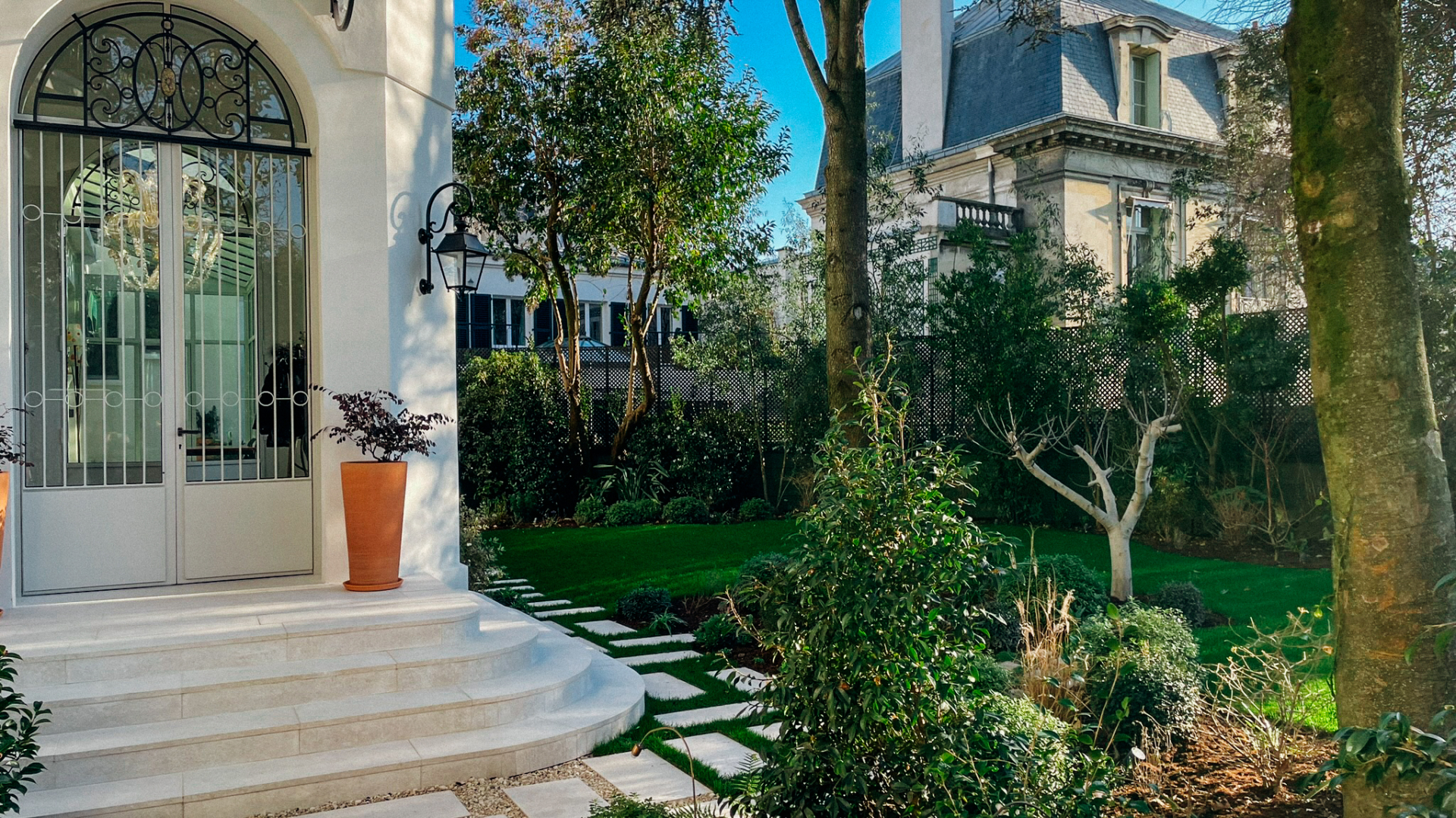 Aménagement d'un jardin à Paris réalisé en 2023 par notre bureau paysagiste, avec allées en pas japonais, pelouse, massifs paysagers et végétation soignée autour d'une demeure de caractère.