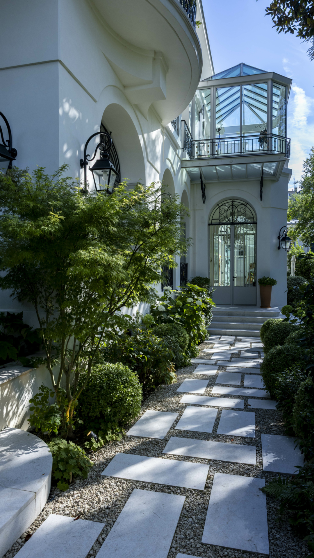 Aménagement d'un jardin à Paris réalisé en 2026 par notre bureau d'études paysager, avec allée en pas japonais, massifs paysagers et végétation soignée autour d'une demeure de caractère.