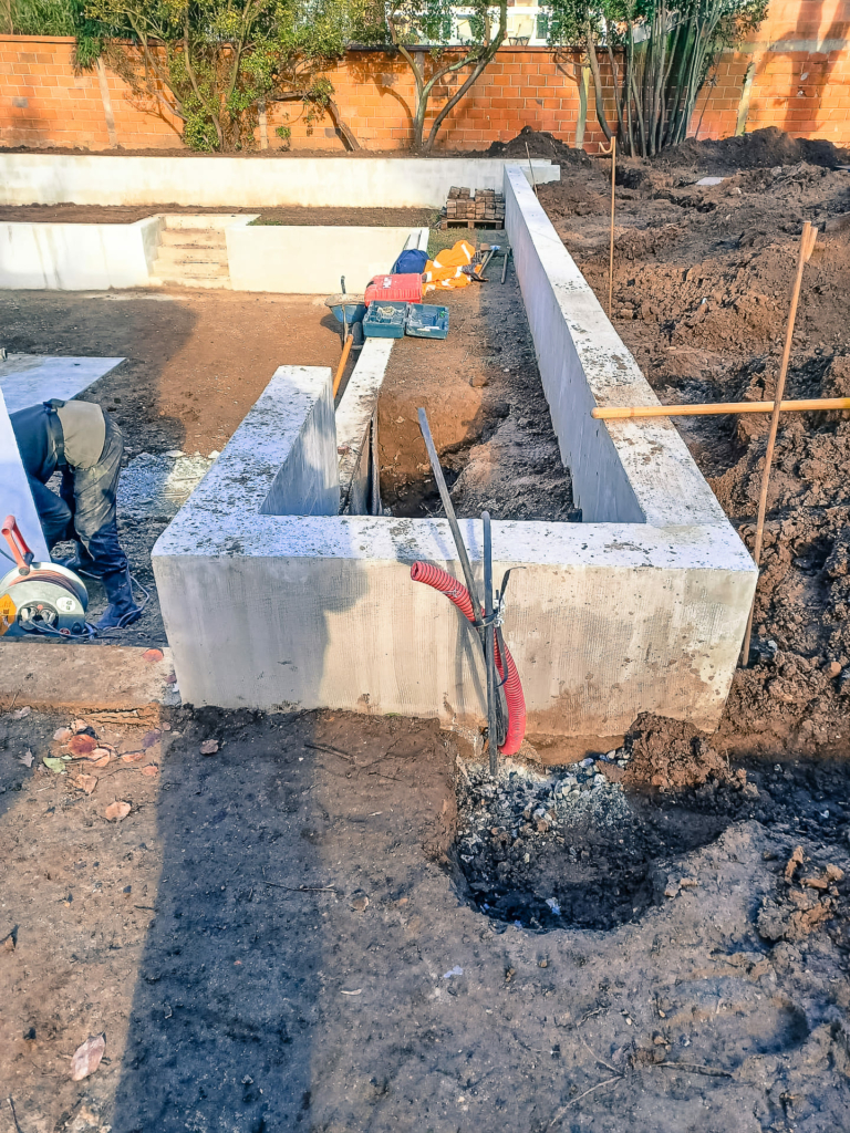 maconnerie-paysagere-projet-piscine Travaux de maçonnerie paysagère en cours avec coffrage en béton, tranchées et préparation du terrain avant aménagement final.