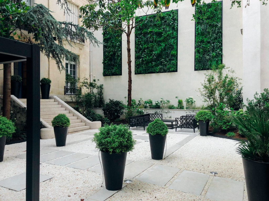 Patio élégant avec murs végétaux de luxe, pots décoratifs et allée minérale.