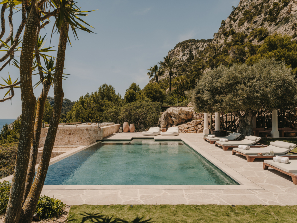 Piscine design entourée de pierre naturelle dans un jardin méditerranéen.