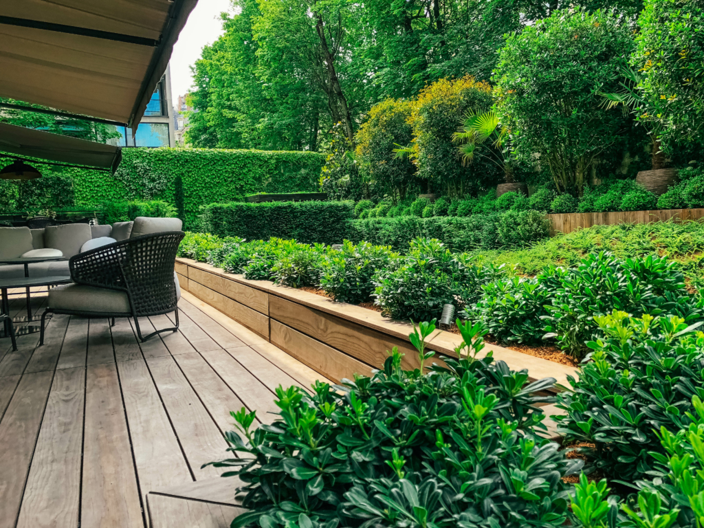 Terrasse en bois donnant sur un jardin paysager dense et verdoyant à Paris.