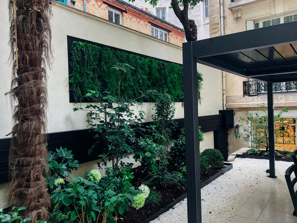Mur végétal de luxe installé sur un mur clair dans un jardin urbain végétalisé.