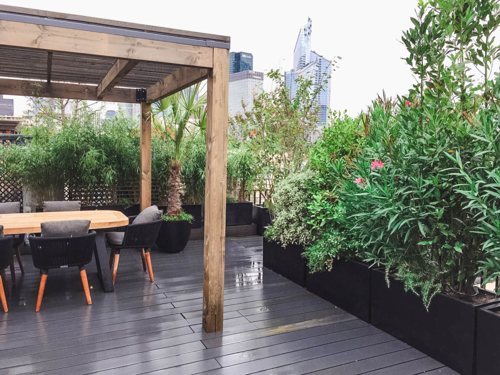 Terrasse d’entreprise aménagée avec pergola en bois et végétation dense