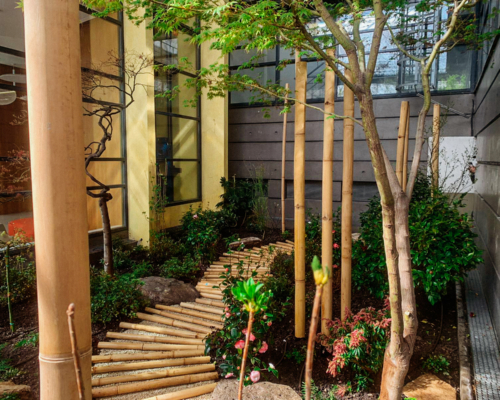 Aménagement paysager entreprise avec chemin en bambou et végétation