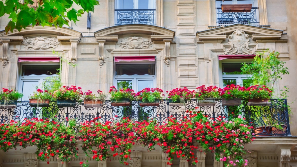 Façade haussmannienne avec balcons fleuris, illustrant l’approche paysagère basée sur la compréhension du lieu et de son architecture.