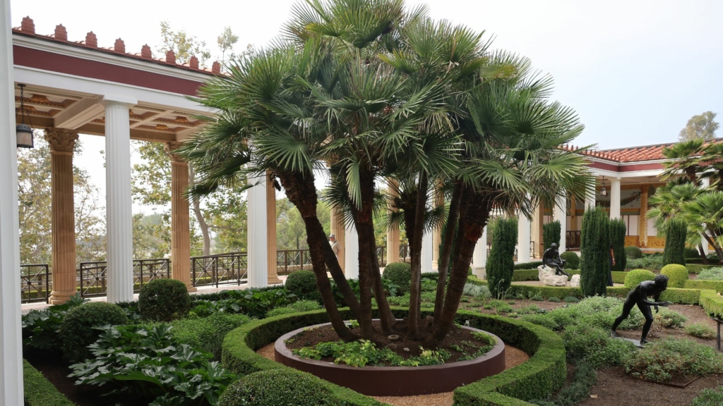 Design paysager de luxe inspiré des jardins classiques, avec palmiers sculpturaux, topiaires et architecture à colonnades