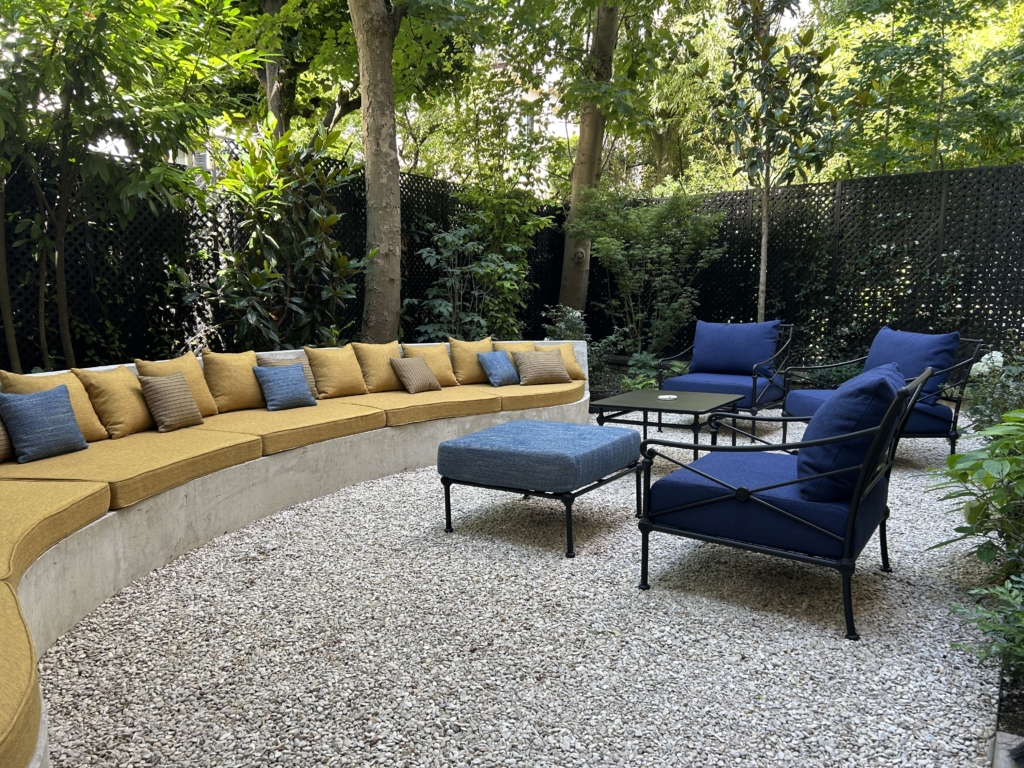 Aménager un jardin urbain ombragé avec banquette maçonnée, fauteuils bleu profond et espace détente sur gravier