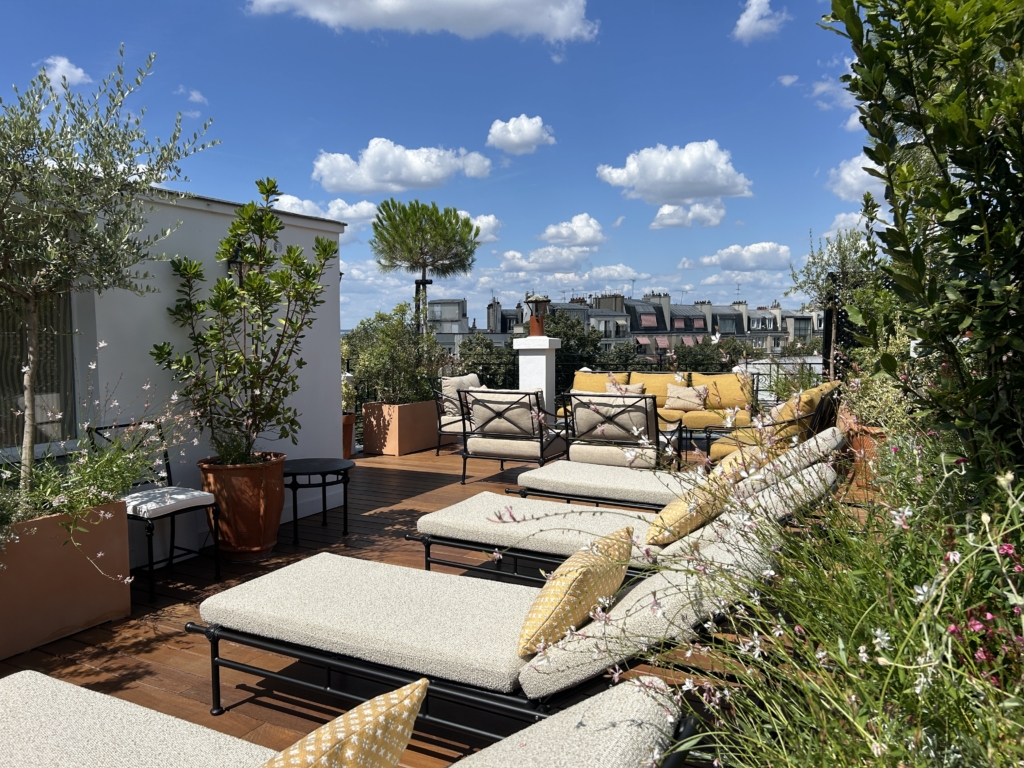 Aménager et optimiser un petit patio en ville : terrasse urbaine en bois avec transats, salon extérieur et plantes méditerranéennes sous ciel bleu ensoleillé