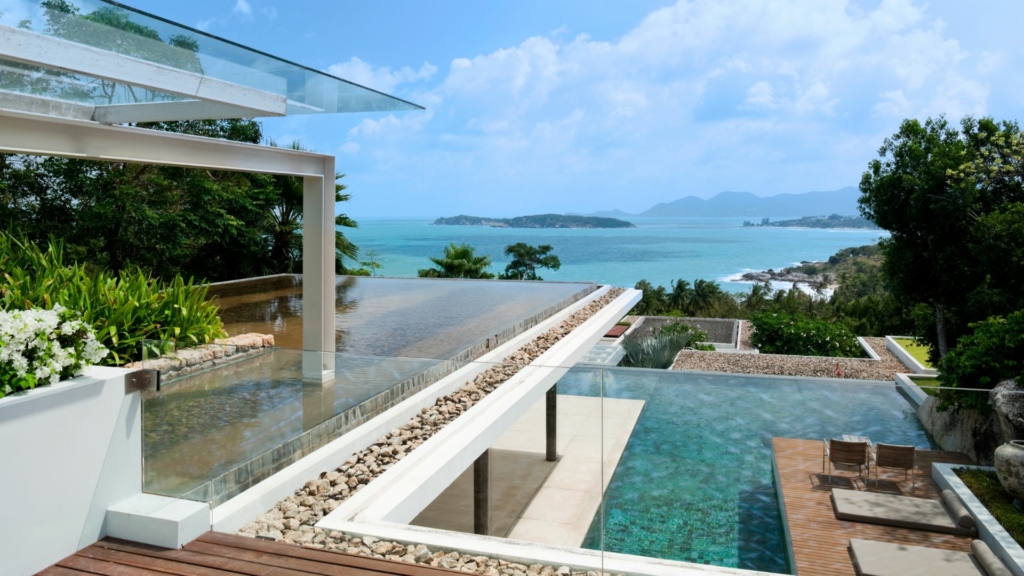 Terrasse contemporaine avec piscine à débordement, aménagement paysager moderne et vue panoramique sur la mer dans un environnement naturel.