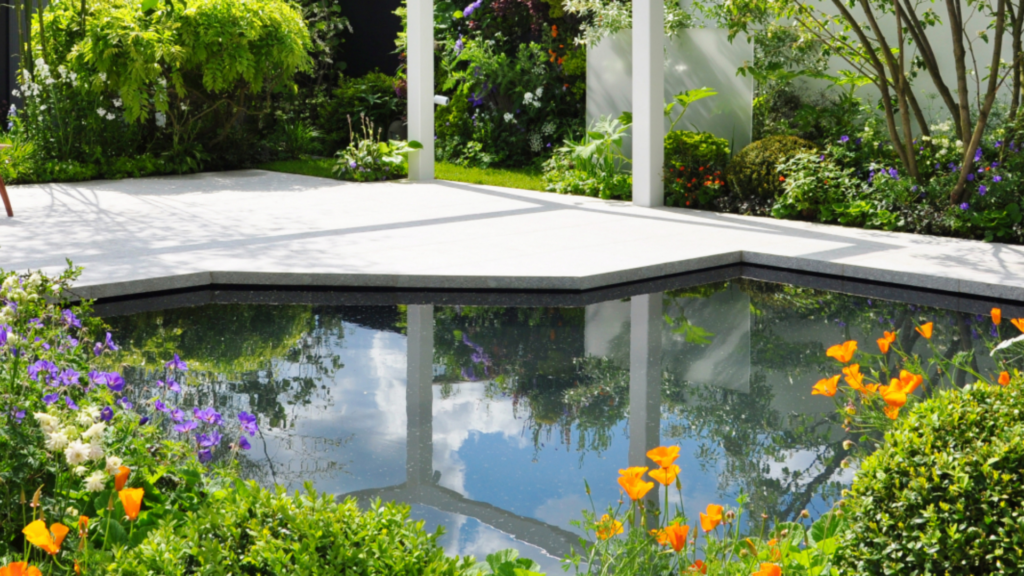 Jardin contemporain au design épuré et géométrique avec bassin, terrasse minérale et végétation paysagée