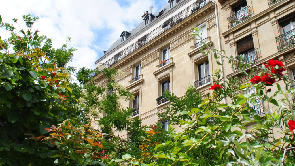 Jardin urbain à Paris avec végétation luxuriante au pied d’un immeuble haussmannien