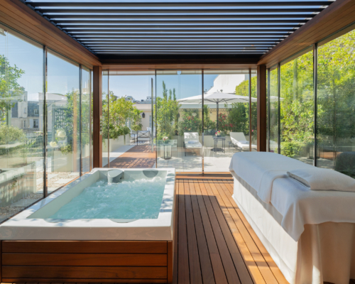Terrasse revisitée du Bristol Paris, hôtel 5 étoiles, avec spa vitré, espace bien-être haut de gamme et jardin paysager élégant.