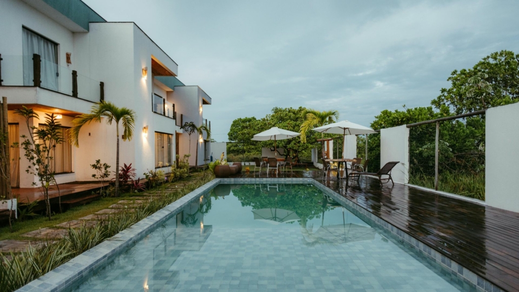 Aménagement extérieur Aménagement extérieur avec piscine rectangulaire, terrasse en bois, coin repas ombragé et jardin paysager autour d’une maison contemporaine.