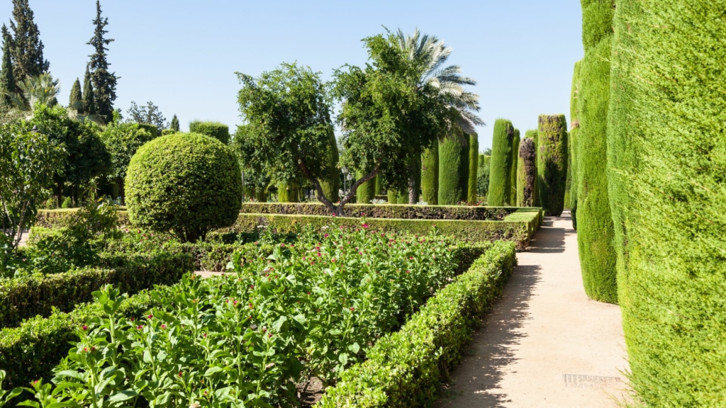 Jardin français Jardin à la française avec allées rectilignes, haies taillées, massifs fleuris et topiaires structurées dans un parc paysager.