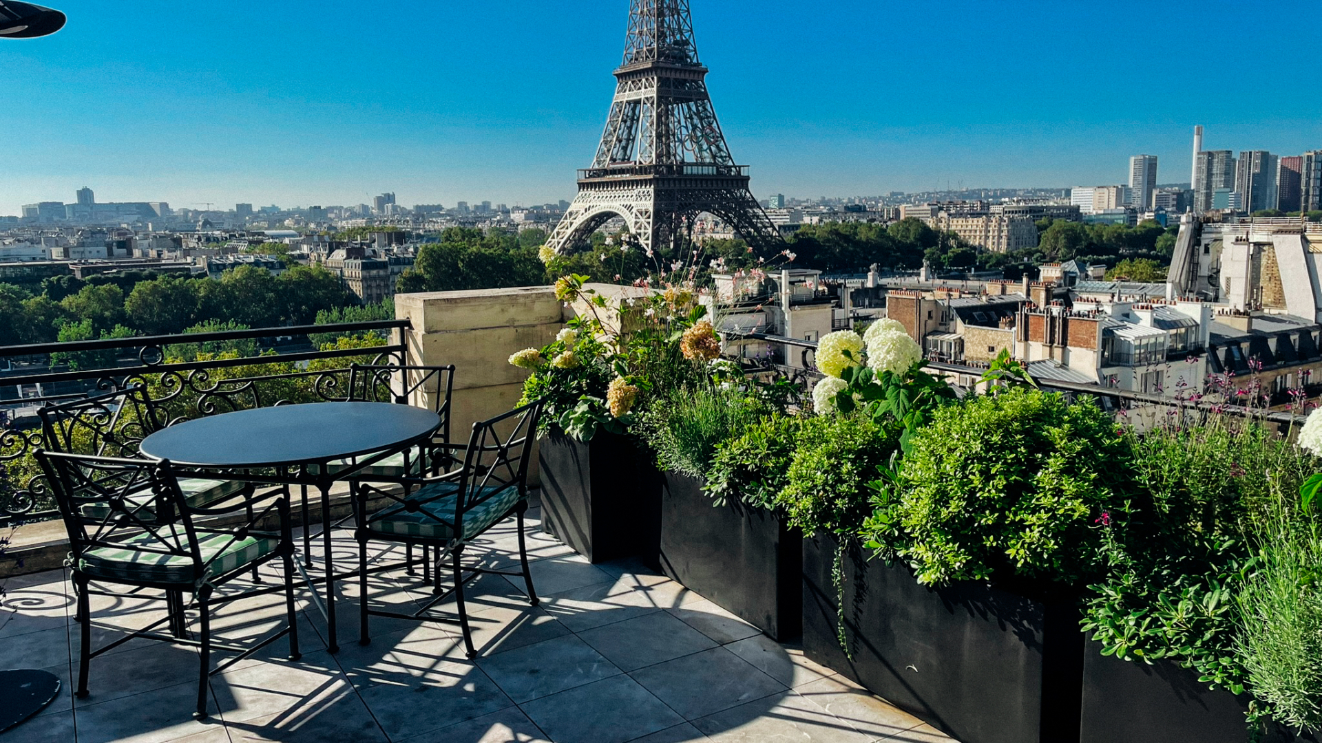 Terrasse aménagée d'un palace parisien avec jardinières paysagées, vue sur la tour Eiffel et espaces extérieurs d'un hôtel de luxe à Paris.