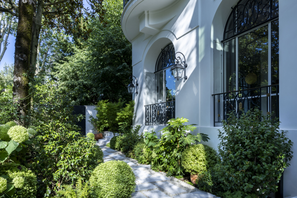 Jardin d'une résidence à Paris. Réalisation par le paysagiste Le Monde des Jardins. 10 juillet 2026. © Laurent Guichardon. Demeure de prestige à Paris avec aménagement paysager haut de gamme, jardin d'exception, massifs végétalisés et entrée élégante dans un cadre résidentiel de luxe.