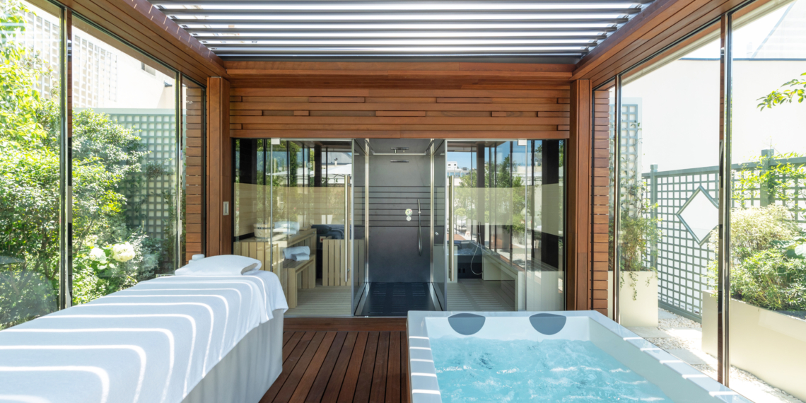 Espace bien-être de la terrasse Suite Eden au Bristol Paris : table de massage et spa sous pergola bois, entre treillages et plantations
